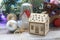 Christmas toy house, balls, cones, branches of spruce, illumination on a wooden surface on a background of a window