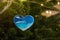 Christmas toy in the shape of a heart with the image of waves of the blue sea hangs on a green tree