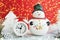 Christmas toy snowman, alarm clock, silver snowflake and tinsel on a red background.