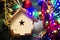 Christmas toy wooden house on the Christmas tree on the colorful lighting background. Beautiful Christmas decorations. Cool bright