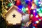 Christmas toy wooden house on the Christmas tree on the colorful lighting background. Beautiful Christmas decorations. Cool bright