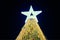 Christmas tree with big white star topper decorated yellow garlands and colorful decorative bulbs