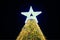 Christmas tree with big white star topper decorated yellow garlands and colorful decorative bulbs
