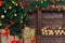 Christmas tree, boxes of gifts. Wooden brown wall with decorative logs coniferous branches