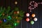 Christmas tree branch, snowflakes, cones, colorful lights and balls on a dark wooden background.
