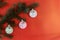 Christmas tree branches decorated by colorful balls on the red sparkled background