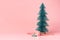 Christmas tree with candy cane on pastel pink studio background.