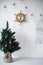 Christmas tree with a card near the white wall with a barometer