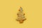 Christmas tree cookie with colorful garlands on a yellow background