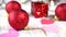 Christmas-tree decorations on a white wooden table. red balls and gift box, pink hearts. Christmas tree lights blink yellow