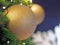 Christmas Tree fir close up decoration with big glitter golden ball has blurred bokeh lightbulb background selective focus.