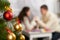 Christmas tree on foreground with defocused romantic young couple sit at the table, happy people and love concept, new year holida