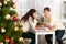 Christmas tree on foreground with defocused romantic young couple sit at the table, happy people and love concept, new year holida