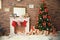 Christmas tree and gifts near decorative fireplace with stockings indoors