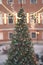 Christmas tree with glowing lights. Old town with pine decorated with garlands, blurred bokeh view