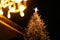 Christmas tree with golden lights and illuminated star in old european city. Merry Christmas