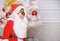 Christmas tree ideas for kids. Boy kid dressed as santa with white artificial beard and red hat near christmas tree