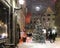 Christmas tree illuminated on evening winter in medieval city street ,lantern light blurred in shop windows vitrines , night sky f