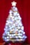 Christmas tree and lights out of focus blurred balls and decorations with tinsel against red background curtains bright colourful