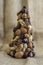 Christmas tree made of autumn ripened brown fruits on jute beige background, chestnuts cones beech nuts almonds walnuts peanuts