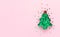 Christmas tree made of cookie form and green confetti at pastel pink background. Creative festive decoration concept.