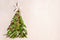 Christmas tree made of green palm thee brunch with small red festive decorations on sand, top view, copy space