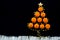 Christmas tree made with orange mandarins and golden star garland at black background