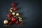 Christmas tree made of red and golden baubles and festive ribbons on dark background with copy space. Christmas concept