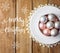 Christmas tree ornaments white pink pearl red balls in vintage ceramic cup on saucer lace napkin. Weathered plank wood. Lettering