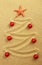 Christmas tree on painting in sand with red starfish and red matt christmas balls