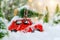 Christmas tree on red car toy with blurred tree background and snow