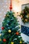 Christmas tree with a red icicle-top is decorated with sparkling garlands and multi-colored balls