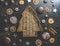 Christmas tree shaped wooden tray on dark concrete table with gingerbread, cookies, dried orange slices and cinnamon sticks.