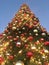 Christmas tree with shiny decorations against a blue sky