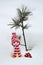 Christmas tree toy - a doll stands against a background of snow next to a small cedar tree.