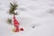 Christmas tree toy - a doll stands against a background of snow next to a small cedar tree.