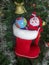 Christmas Tree Toy Santa Claus with a ball of Earth, Golden Bell, Garland, Xmas Red boot against the backdrop of a green artificia