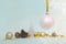 Christmas tree white ball hanging on a gold ribbon on a light blue background with Christmas balls, pine cones and gold