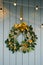 A Christmas tree wreath hangs on a dusty blue wall