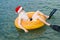 Christmas vacation. Teenage boy relaxes on inflatable circle on sea waves in flippers and red Santa hat, vacation and travel