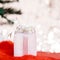 Christmas white gift box with a large bow standing on red hat santa calus against a background bokeh of twinkling golden bokeh