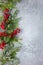 Christmas or winter background with a border of green and frosted evergreen branches and red berries on a grey vintage board. Flat