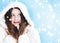 Christmas and winter holiday portrait of young woman in white hooded fur coat, snow on blue background, fashion and