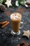Christmas or winter hot chocolate drink. Tall glass up of fresh coffee latte with whipped cream, isolated on dark background