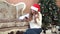 Christmas Woman dressed white sweater Santa hat sitting on floor near Christmas tree