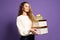 Christmas woman in white seater holds many gifts boxes on purple studio background. Christmas concept. Sales