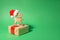 Christmas wooden reindeer wearing red Santa hat on a Christmas gift on a green paper