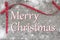 Christmas words on wooden snow covered board with red ribbon