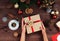 Christmas workplace top view. Girlâ€™s hands on the wooden table holding Christmas present. Christmas wreath