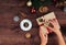 Christmas workplace top view. Girlâ€™s hands on the wooden table holding Christmas present. Christmas wreath